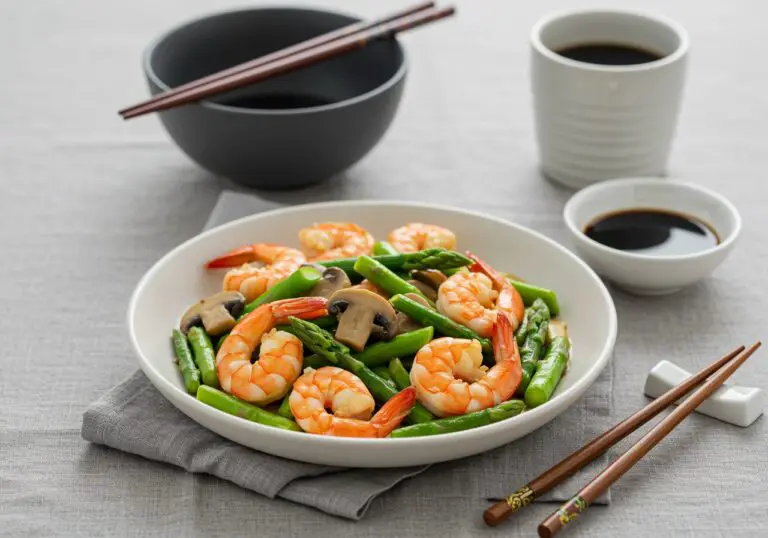 Deliciously served Shrimp and Asparagus Stir-Fry with Mushrooms on a dinner table, complete with chopsticks and soy sauce for an authentic dining experience.